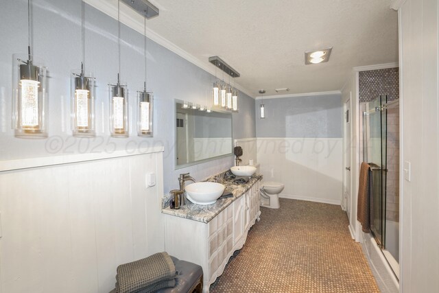 620 N Main St, Stratford, TX 79084 - bathroom with ornamental molding, an enclosed shower, double vanity, toilet, and a textured ceiling