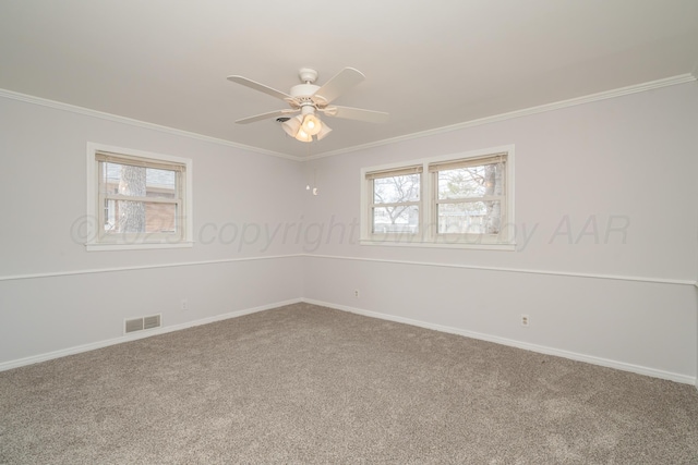 carpeted spare room featuring ceiling fan, crown molding, and a healthy amount of sunlight