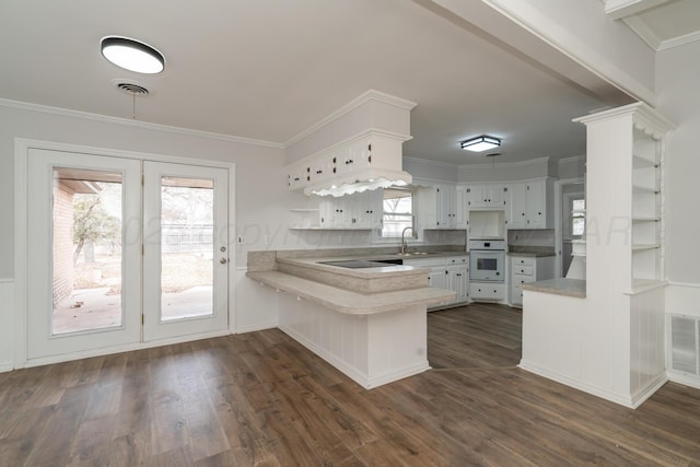 kitchen featuring sink, white cabinetry, ornamental molding, kitchen peninsula, and oven