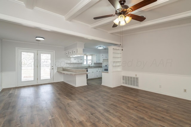 kitchen with ornamental molding, dark hardwood / wood-style flooring, kitchen peninsula, beam ceiling, and white cabinets