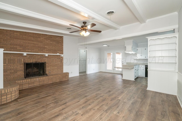 unfurnished living room featuring beamed ceiling, ornamental molding, dark wood-type flooring, and a brick fireplace