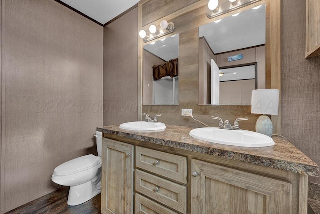 bathroom featuring vanity, wood-type flooring, ornamental molding, and toilet