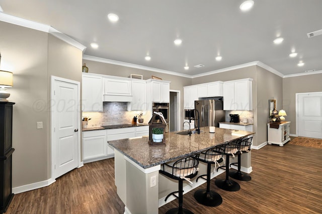 2701 Daybreak Ln, Amarillo, TX 79124 - kitchen with stainless steel appliances, ornamental molding, a breakfast bar, decorative backsplash, and an island with sink