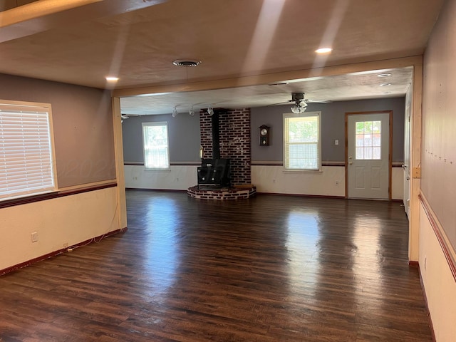 224 Beach St, Hereford, TX 79045 - unfurnished living room with ceiling fan, wainscoting, a wood stove, wood finished floors, and baseboards