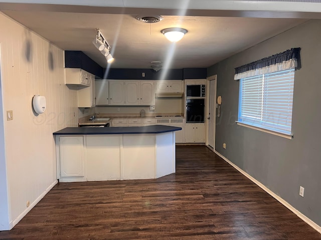 224 Beach St, Hereford, TX 79045 - kitchen featuring a sink, dark countertops, dark wood-style flooring, and a peninsula