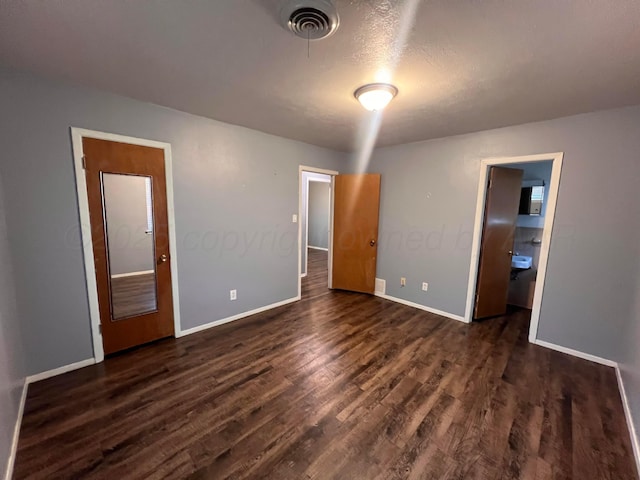 224 Beach St, Hereford, TX 79045 - unfurnished bedroom featuring connected bathroom, baseboards, visible vents, and dark wood-style floors