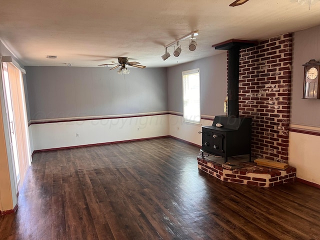 224 Beach St, Hereford, TX 79045 - unfurnished living room featuring track lighting, a wood stove, a ceiling fan, baseboards, and wood finished floors