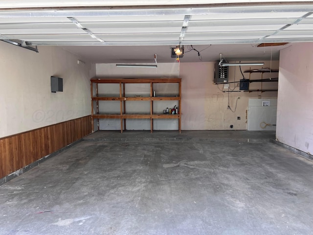 224 Beach St, Hereford, TX 79045 - garage featuring electric panel, wood walls, a garage door opener, and a wainscoted wall