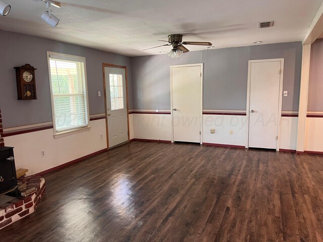 224 Beach St, Hereford, TX 79045 - unfurnished living room with a ceiling fan, a wood stove, dark wood-style flooring, and visible vents