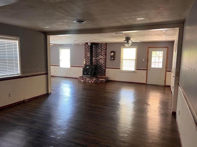 224 Beach St, Hereford, TX 79045 - unfurnished living room featuring a wood stove, a ceiling fan, wood finished floors, and a healthy amount of sunlight