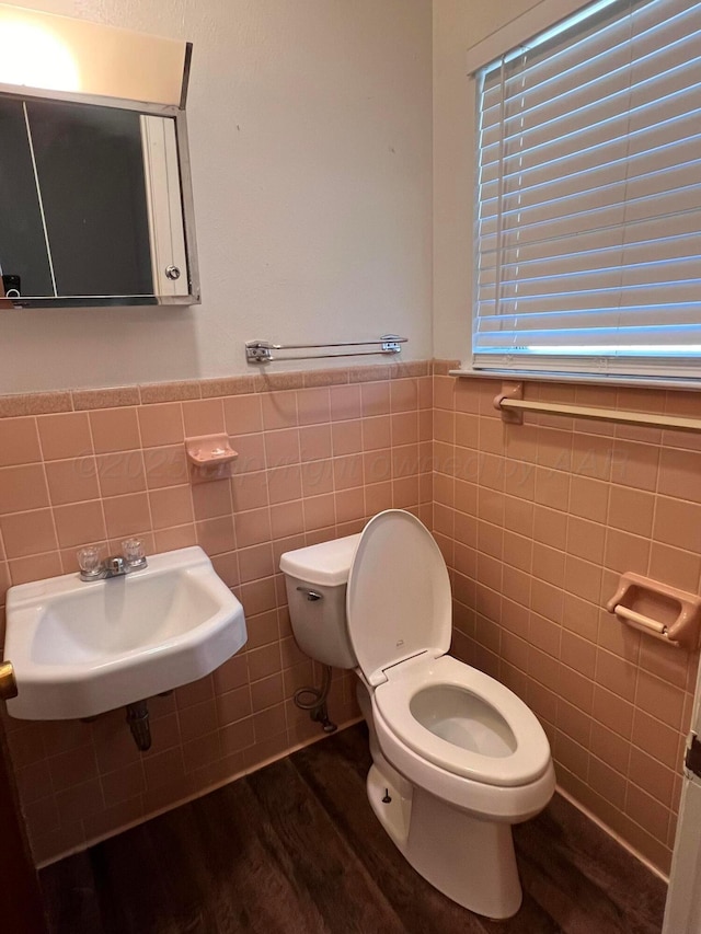 224 Beach St, Hereford, TX 79045 - bathroom with tile walls, wood finished floors, a sink, a wainscoted wall, and toilet