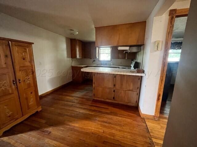 819 Ave N, Sunray, TX 79086 - kitchen with light countertops, dark wood-style floors, a peninsula, and brown cabinetry