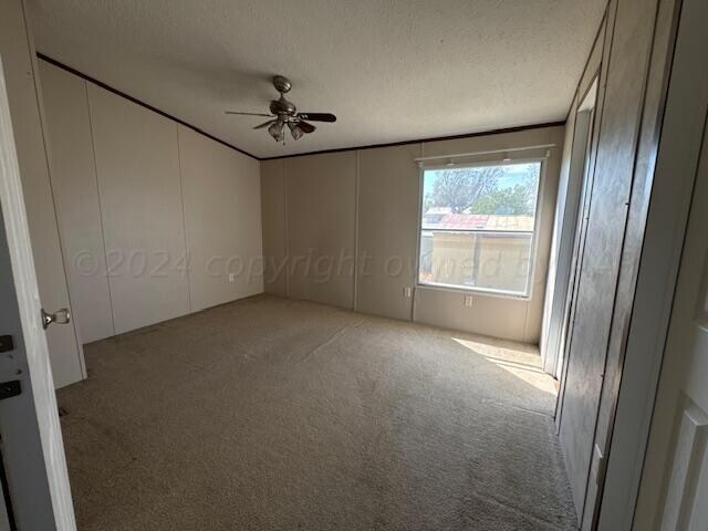 carpeted empty room featuring ceiling fan and a textured ceiling