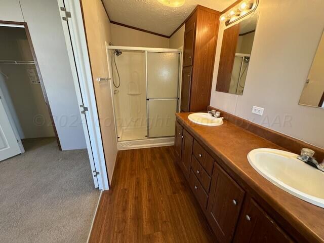 bathroom featuring a shower with door, ornamental molding, a textured ceiling, hardwood / wood-style floors, and vanity