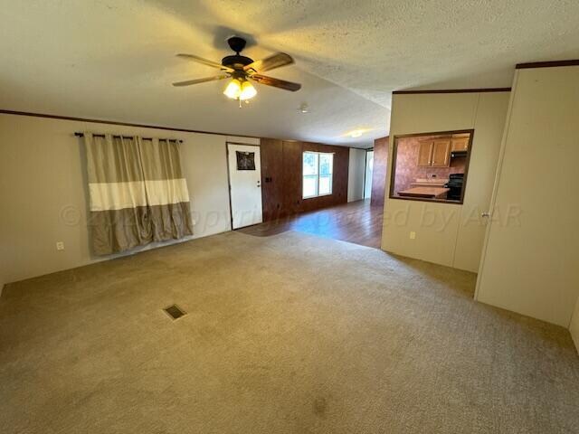 empty room with a textured ceiling, carpet flooring, lofted ceiling, and ceiling fan