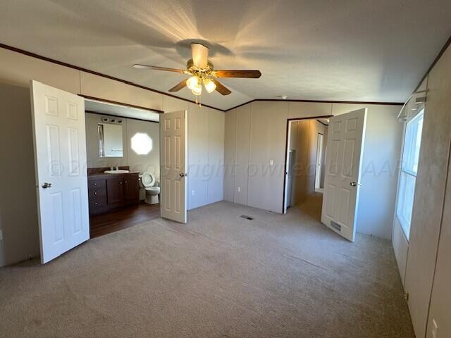 unfurnished bedroom featuring lofted ceiling, light carpet, ceiling fan, and ensuite bath