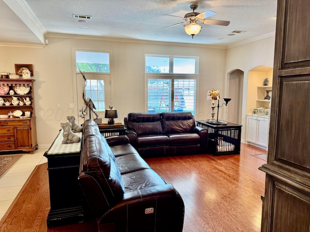 5007 Wesley Rd, Amarillo, TX 79119 - living room featuring arched walkways, a ceiling fan, crown molding, light wood-style flooring, and a textured ceiling