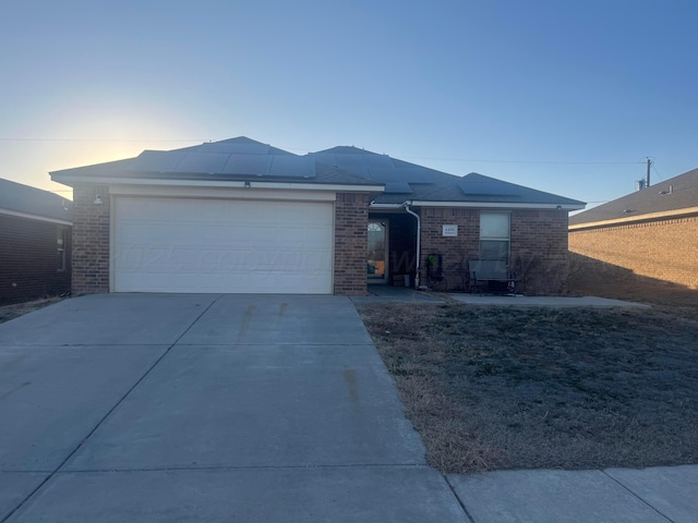 single story home with concrete driveway, brick siding, and an attached garage