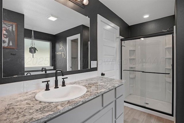 full bathroom featuring vanity, a shower stall, and wood finished floors