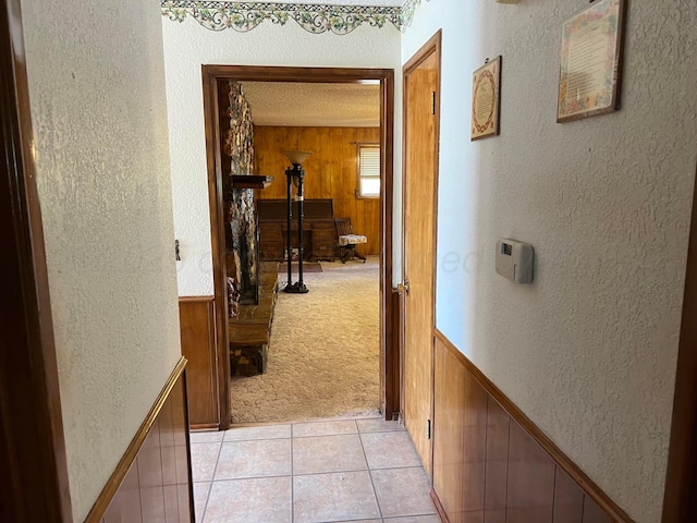 415 Mesquite Ave, Amarillo, TX 79108 - corridor with wooden walls, a textured wall, light tile patterned flooring, and light carpet