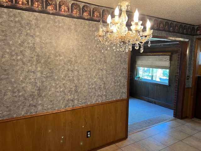 415 Mesquite Ave, Amarillo, TX 79108 - unfurnished dining area with a chandelier, carpet floors, a textured ceiling, tile patterned floors, and wood walls