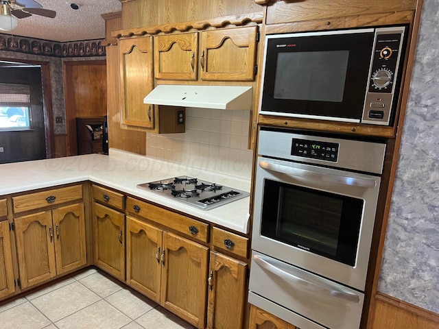 415 Mesquite Ave, Amarillo, TX 79108 - kitchen featuring stainless steel appliances, a warming drawer, brown cabinets, light countertops, and light tile patterned flooring