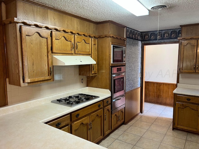 415 Mesquite Ave, Amarillo, TX 79108 - kitchen featuring appliances with stainless steel finishes, a warming drawer, under cabinet range hood, light countertops, and a textured ceiling