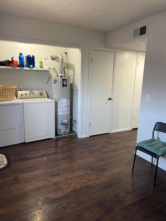 clothes washing area with washing machine and clothes dryer, gas water heater, dark hardwood / wood-style floors, and a textured ceiling