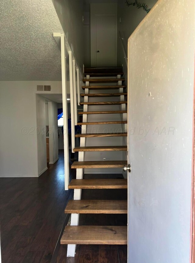 stairs with hardwood / wood-style floors and a textured ceiling