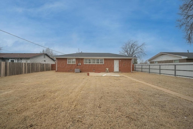 rear view of property with a fenced backyard, a lawn, cooling unit, and brick siding