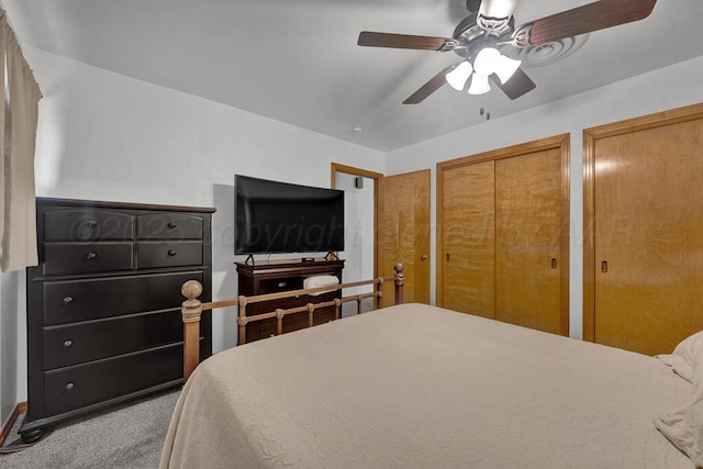 carpeted bedroom with ceiling fan and multiple closets