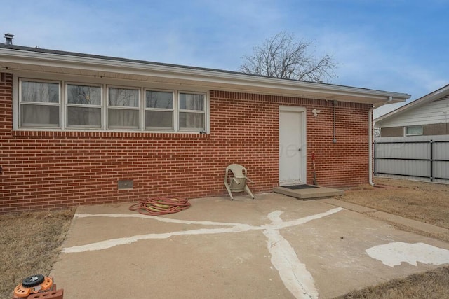 rear view of property with brick siding, fence, and a patio