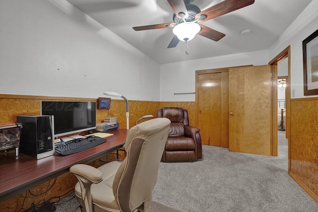 carpeted home office featuring a wainscoted wall, wood walls, and ceiling fan