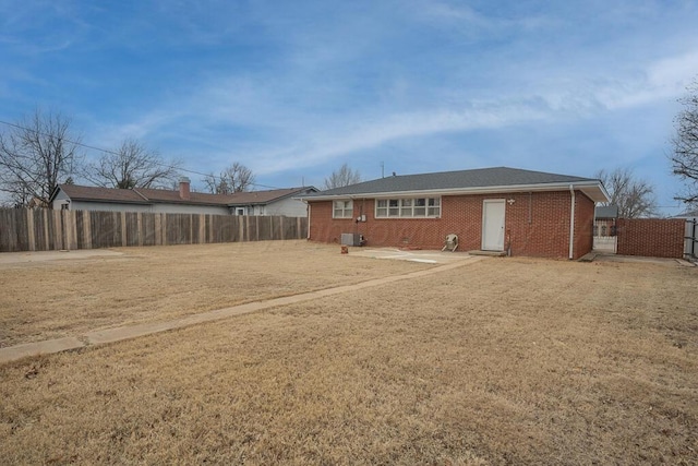 rear view of house with a yard, a fenced backyard, and brick siding