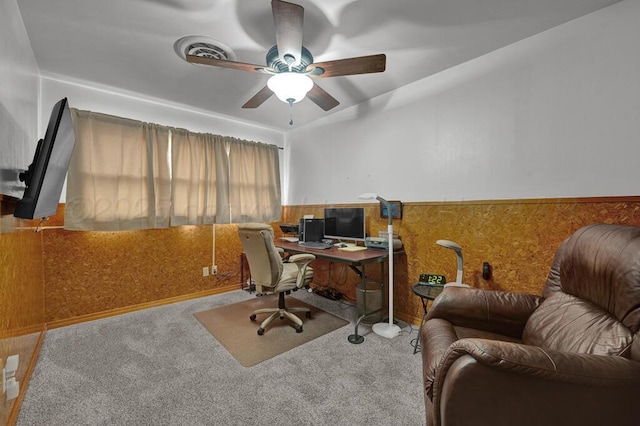 office area with carpet floors, a wainscoted wall, and a ceiling fan