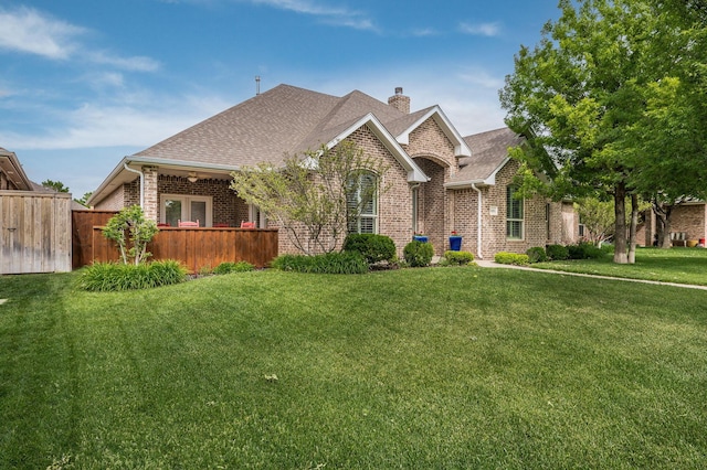 view of front of home featuring brick siding, a chimney, a front yard, and fence