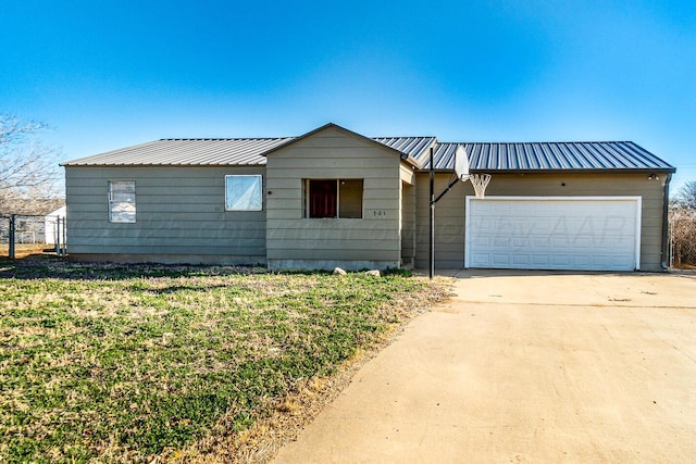 ranch-style home featuring metal roof, a front yard, concrete driveway, and an attached garage