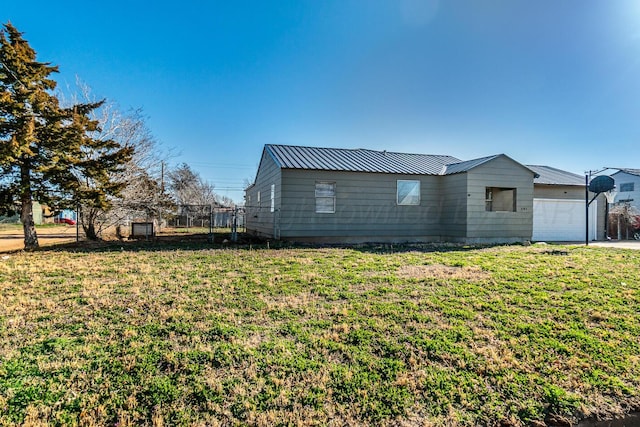 view of side of property with an attached garage, metal roof, a yard, and fence