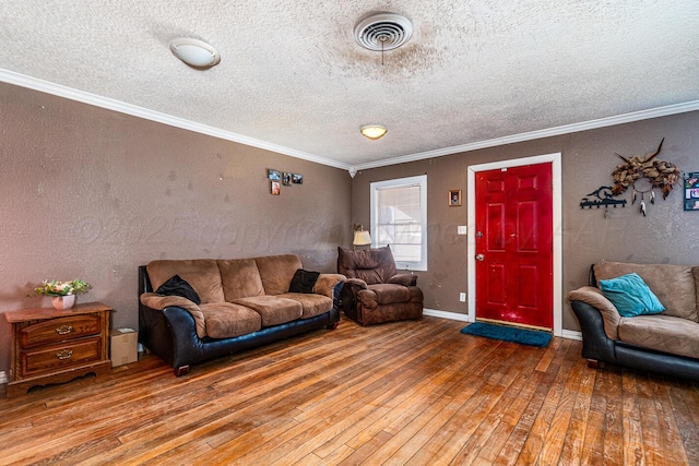 living area with hardwood / wood-style floors, a textured wall, visible vents, and ornamental molding