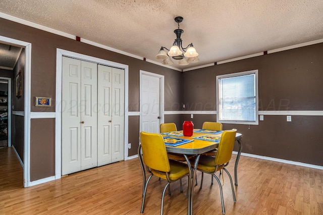 dining room with an inviting chandelier, light wood-type flooring, and ornamental molding