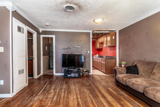 living area featuring visible vents, wood-type flooring, and crown molding