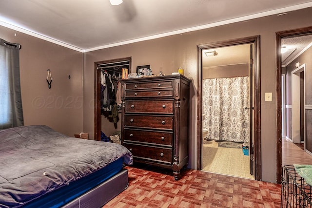 bedroom featuring a closet, ensuite bath, and crown molding