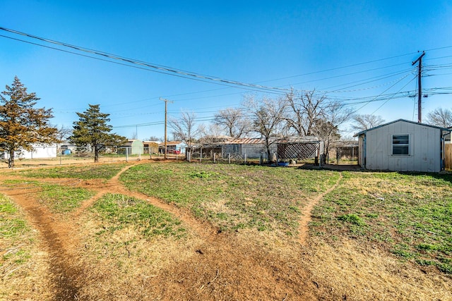 view of yard featuring an outbuilding, a storage shed, and fence