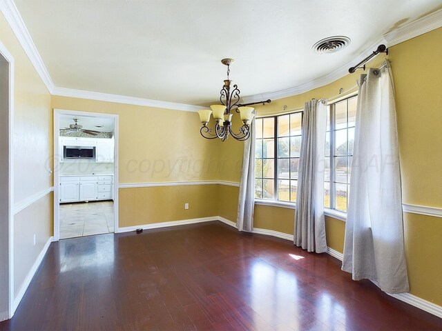 empty room featuring ornamental molding, dark hardwood / wood-style floors, and a notable chandelier