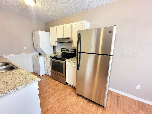1312 Coffee St, Pampa, TX 79065 - kitchen featuring light hardwood / wood-style floors, appliances with stainless steel finishes, white cabinetry, and stacked washer / drying machine