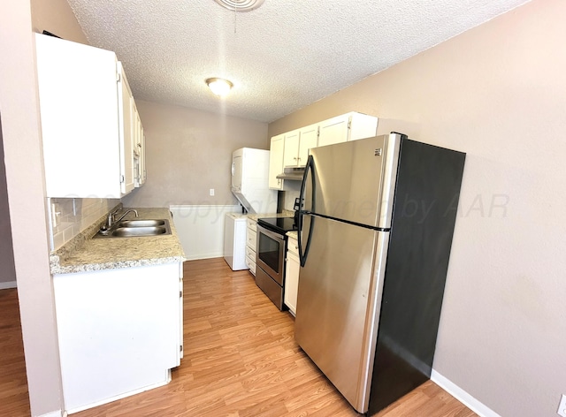 1312 Coffee St, Pampa, TX 79065 - kitchen with light hardwood / wood-style flooring, stainless steel appliances, white cabinets, stacked washing maching and dryer, and sink