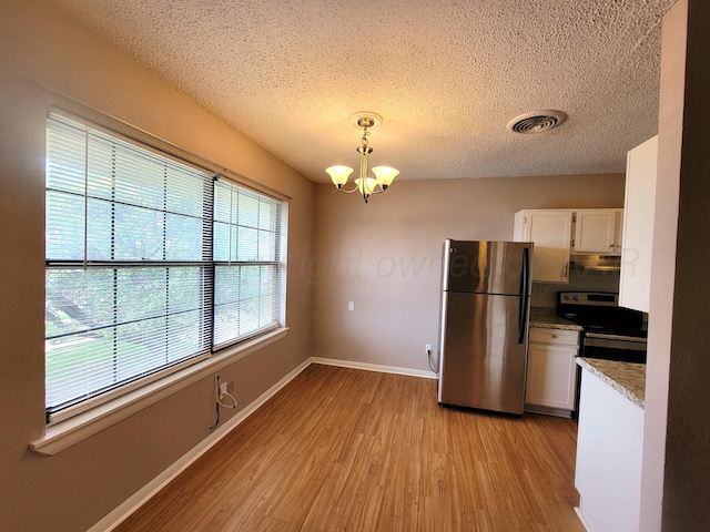 1312 Coffee St, Pampa, TX 79065 - kitchen featuring appliances with stainless steel finishes, light hardwood / wood-style flooring, a chandelier, pendant lighting, and white cabinetry