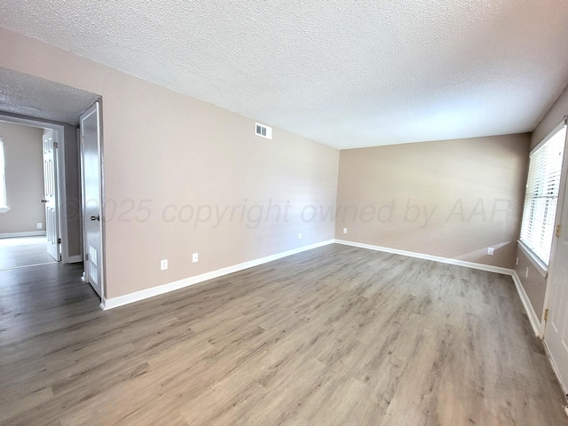 empty room with wood-type flooring and a textured ceiling