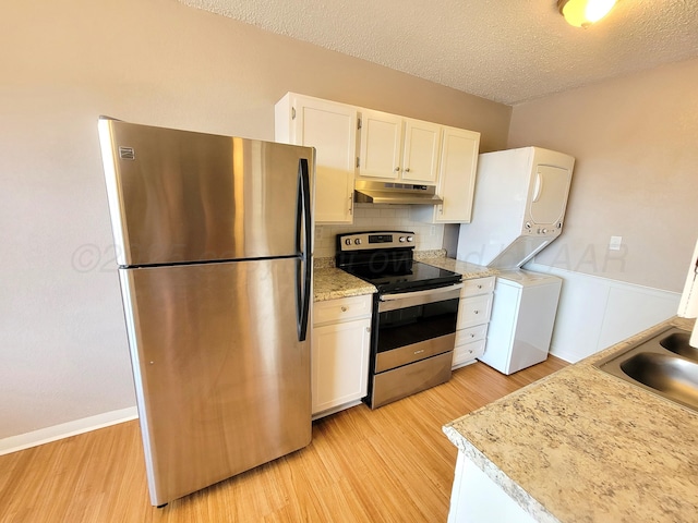 1312 Coffee St, Pampa, TX 79065 - kitchen featuring white cabinetry, light hardwood / wood-style floors, appliances with stainless steel finishes, and stacked washer / drying machine