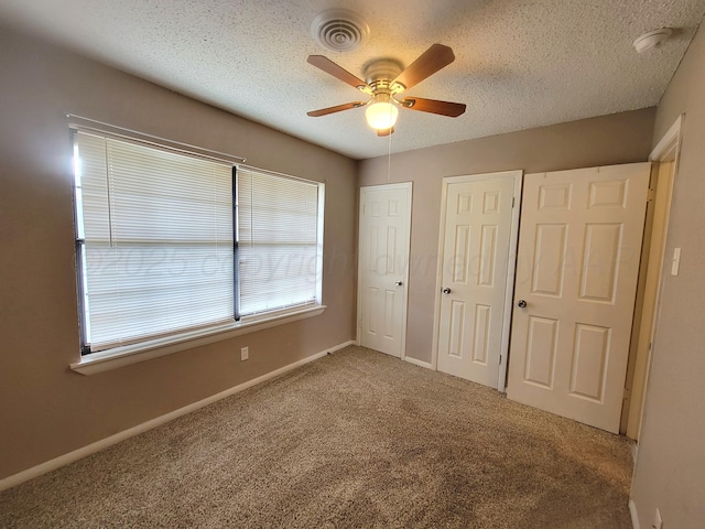 1312 Coffee St, Pampa, TX 79065 - unfurnished bedroom with a textured ceiling, carpet flooring, two closets, and ceiling fan